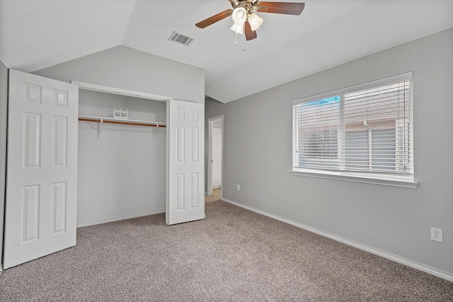 unfurnished bedroom featuring ceiling fan, vaulted ceiling, a closet, and carpet flooring