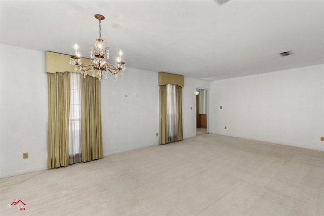 empty room with light colored carpet and a notable chandelier