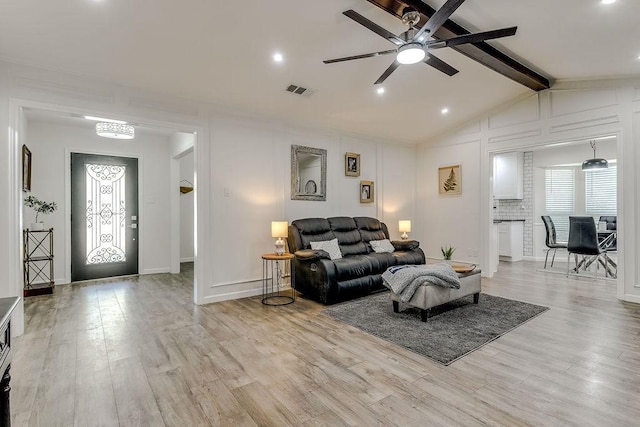 living room with ceiling fan, vaulted ceiling with beams, and light hardwood / wood-style floors