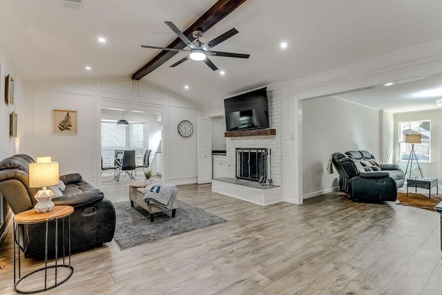 living room featuring ceiling fan, a healthy amount of sunlight, a fireplace, and light hardwood / wood-style floors