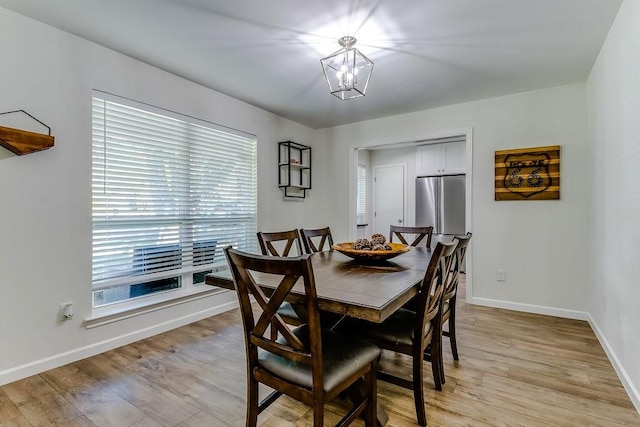 dining space with a healthy amount of sunlight, light wood-type flooring, and an inviting chandelier