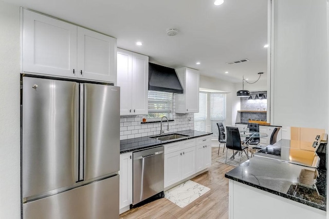 kitchen with light wood-type flooring, appliances with stainless steel finishes, white cabinetry, and sink