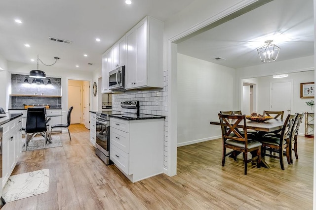 kitchen featuring light wood-type flooring, appliances with stainless steel finishes, backsplash, and white cabinetry