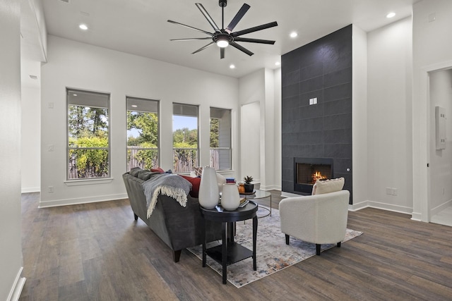 living room featuring ceiling fan, dark hardwood / wood-style flooring, and a tile fireplace