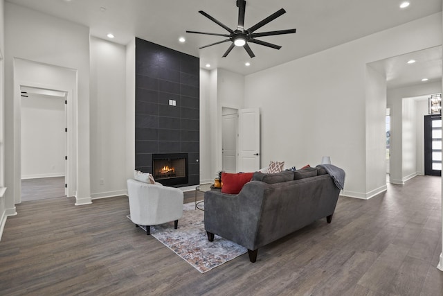 living room with ceiling fan, dark wood-type flooring, and a tiled fireplace