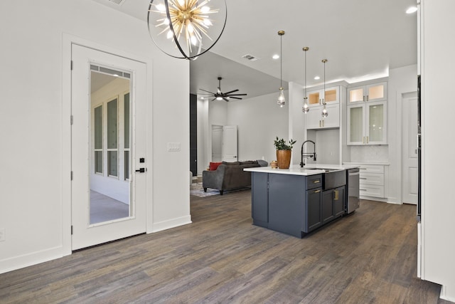 kitchen featuring an island with sink, dark hardwood / wood-style floors, hanging light fixtures, ceiling fan with notable chandelier, and white cabinets