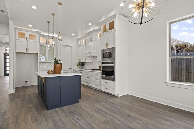 kitchen with tasteful backsplash, white cabinets, appliances with stainless steel finishes, and a kitchen island