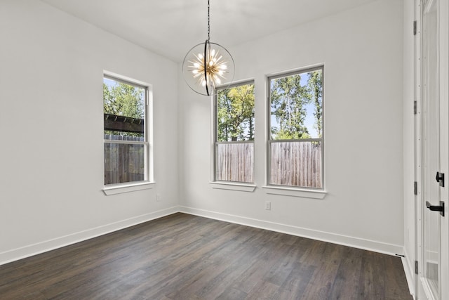 spare room featuring dark hardwood / wood-style floors and a chandelier