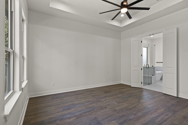 empty room with dark hardwood / wood-style floors, a healthy amount of sunlight, and a raised ceiling