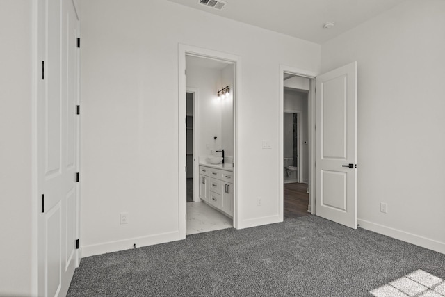 unfurnished bedroom with ensuite bathroom and light colored carpet