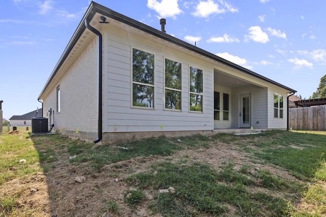 back of house with central AC and a yard