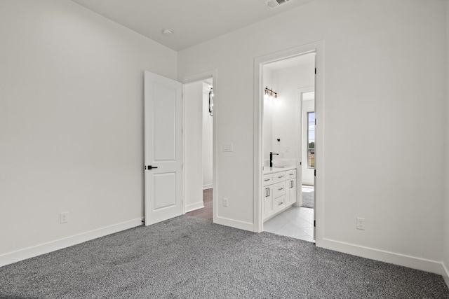 unfurnished bedroom with light colored carpet, connected bathroom, and sink