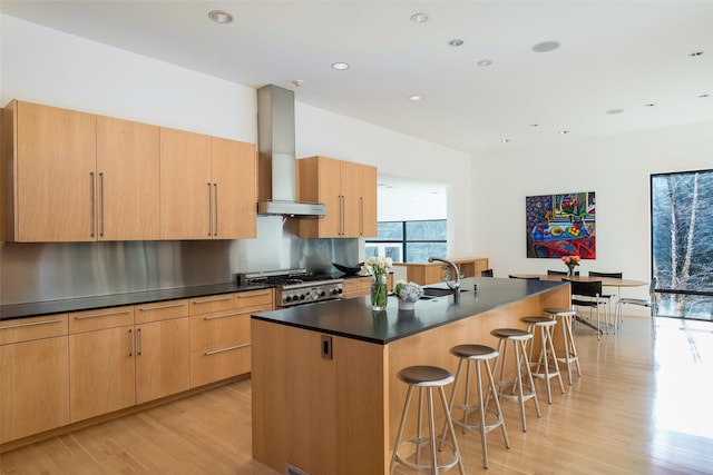 kitchen with island range hood, light hardwood / wood-style floors, a kitchen island with sink, range, and a breakfast bar