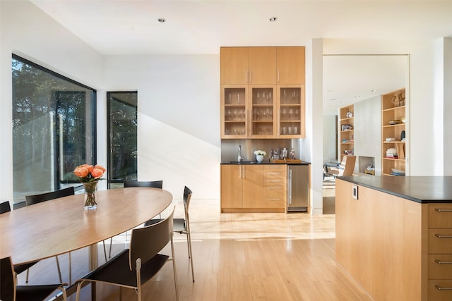 dining area with wine cooler, light hardwood / wood-style floors, and bar area