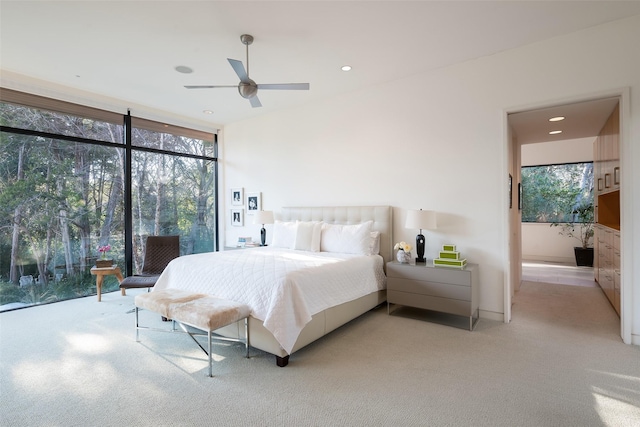 bedroom with ceiling fan, light carpet, and floor to ceiling windows