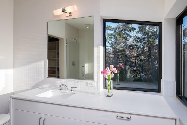 bathroom featuring walk in shower, vanity, and tile walls