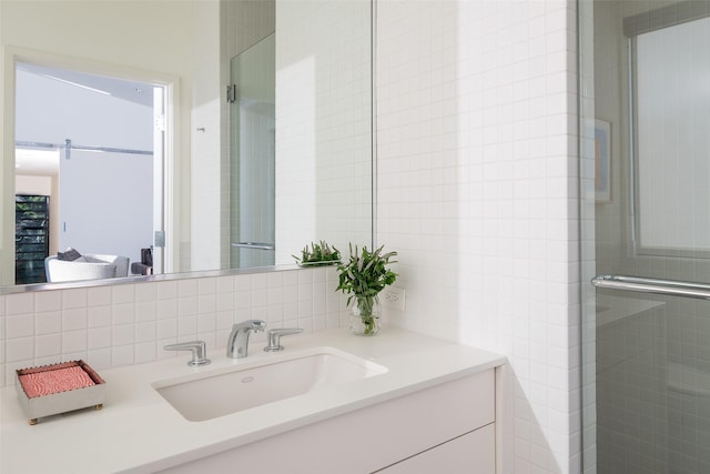 bathroom featuring vanity, tile walls, tasteful backsplash, and a shower with door