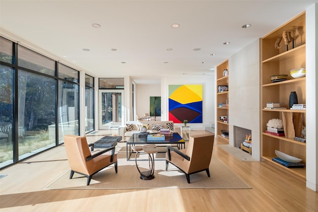 living room featuring built in shelves, a wall of windows, and light wood-type flooring