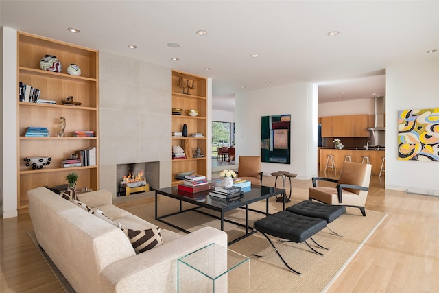 living room with built in shelves, light hardwood / wood-style flooring, and a fireplace