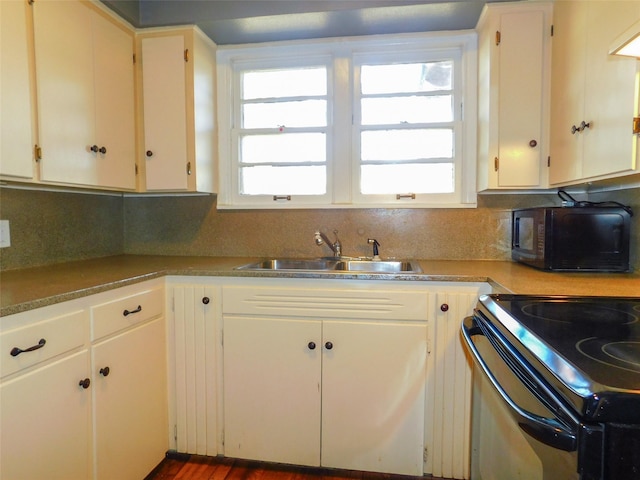 kitchen featuring decorative backsplash, electric range, sink, and white cabinetry