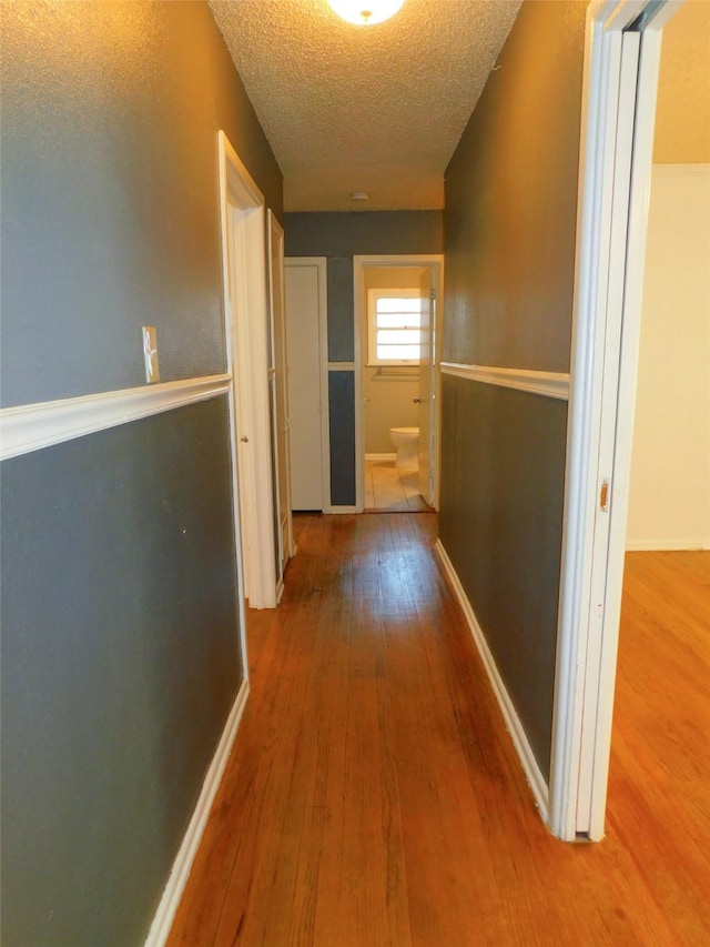 hallway with hardwood / wood-style floors and a textured ceiling