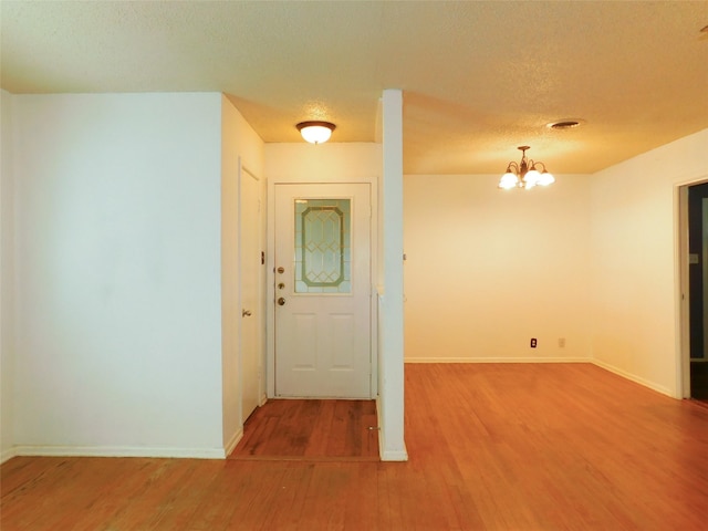 interior space with hardwood / wood-style floors, a textured ceiling, and an inviting chandelier