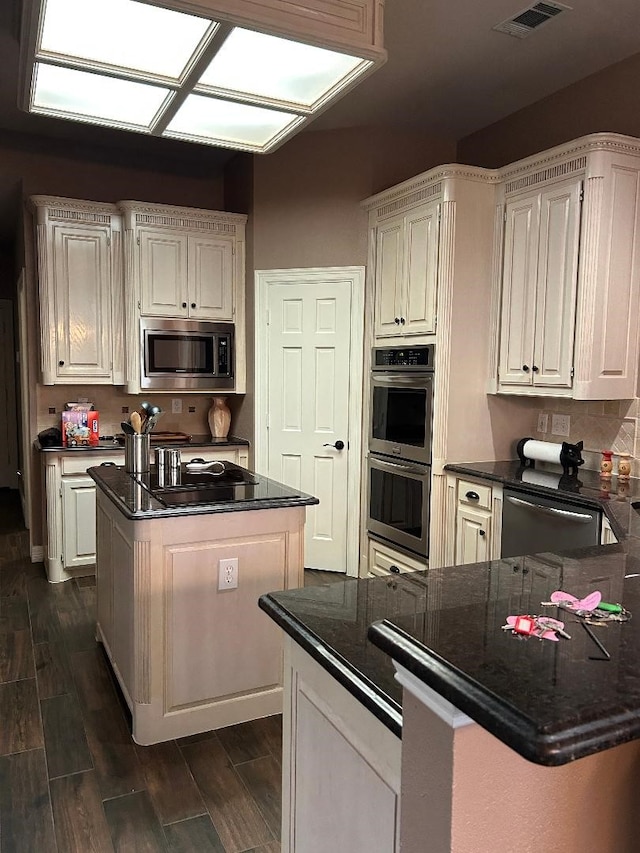 kitchen featuring white cabinetry, stainless steel appliances, and dark stone counters