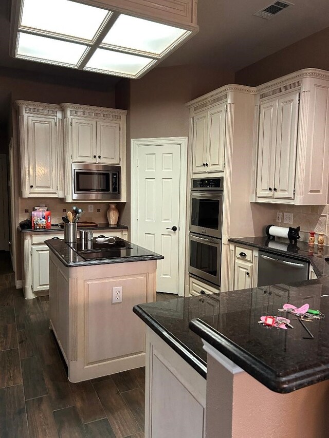 kitchen featuring dark stone countertops, appliances with stainless steel finishes, and white cabinets