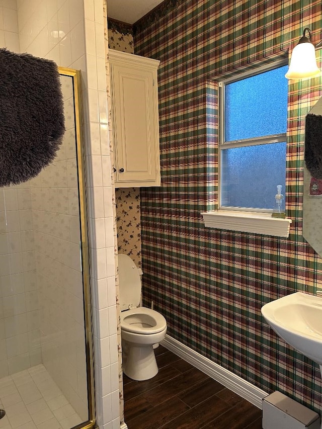 bathroom featuring toilet, a shower with shower door, and hardwood / wood-style floors