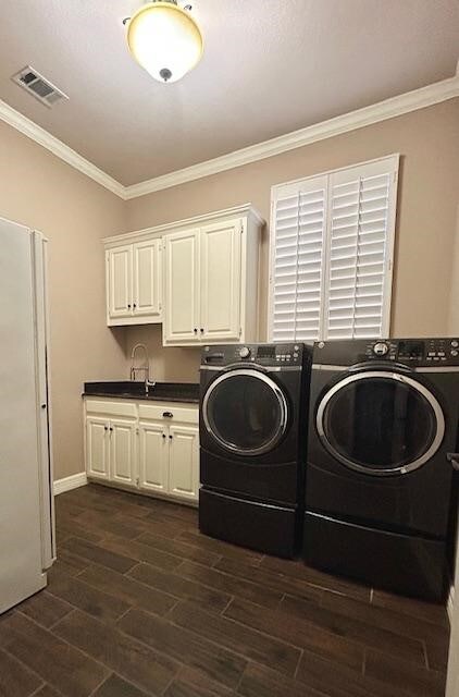 laundry room featuring cabinets, washing machine and dryer, crown molding, and dark hardwood / wood-style flooring