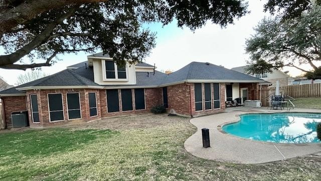 rear view of house with central AC unit, a yard, a patio area, and a fenced in pool