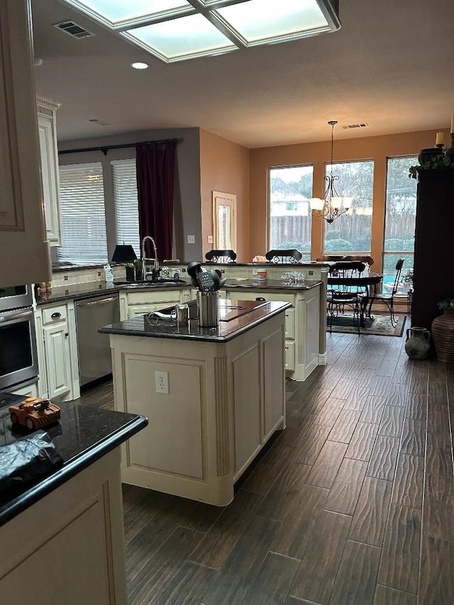 kitchen featuring a kitchen island, decorative light fixtures, stainless steel appliances, sink, and kitchen peninsula