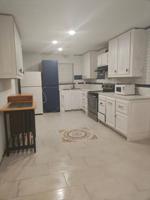 kitchen with backsplash, sink, white appliances, light tile patterned flooring, and white cabinets