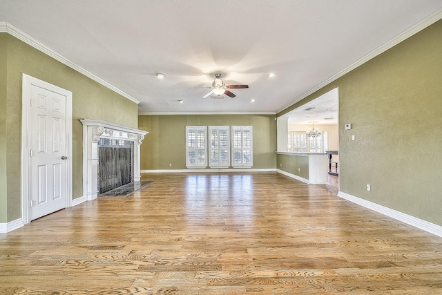 unfurnished living room featuring crown molding, a high end fireplace, ceiling fan with notable chandelier, and light hardwood / wood-style flooring