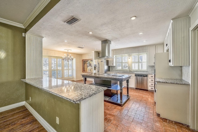 kitchen with appliances with stainless steel finishes, decorative light fixtures, white cabinetry, island exhaust hood, and crown molding