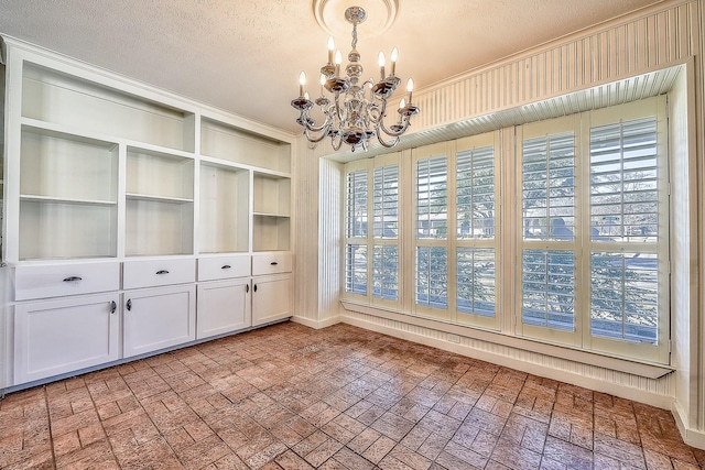 unfurnished dining area with a notable chandelier and a textured ceiling