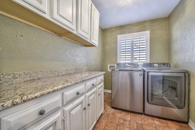 laundry area featuring cabinets, washer and dryer, and a textured ceiling