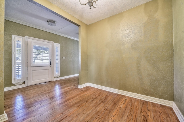 foyer entrance featuring hardwood / wood-style floors, crown molding, and a textured ceiling