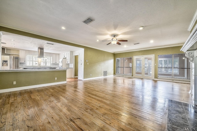 unfurnished living room with hardwood / wood-style flooring, ceiling fan, ornamental molding, and a textured ceiling