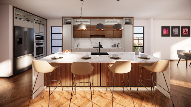 kitchen featuring tasteful backsplash, modern cabinets, appliances with stainless steel finishes, and a breakfast bar area