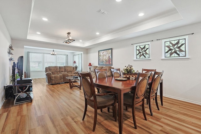 dining area with light hardwood / wood-style flooring and a raised ceiling