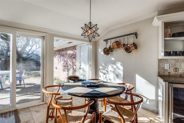 dining room with vaulted ceiling, a chandelier, wine cooler, and ornamental molding