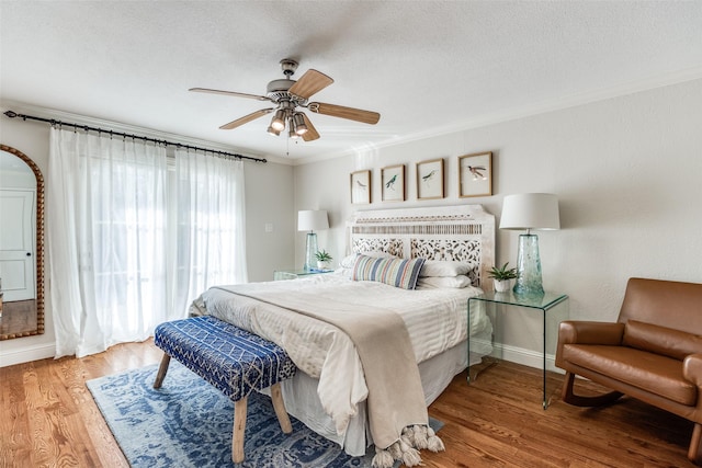 bedroom featuring ceiling fan, a textured ceiling, hardwood / wood-style flooring, and crown molding