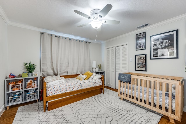 bedroom featuring a textured ceiling, ceiling fan, a closet, and crown molding