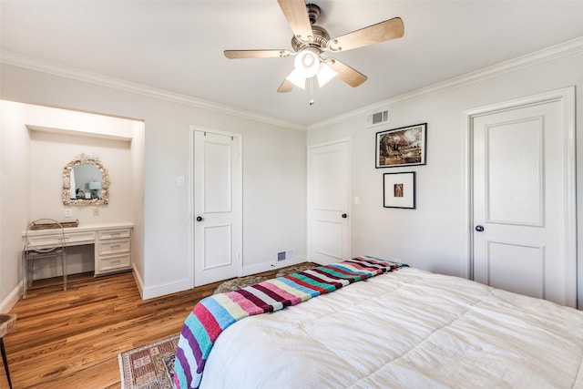 bedroom featuring ceiling fan, crown molding, built in desk, and hardwood / wood-style flooring