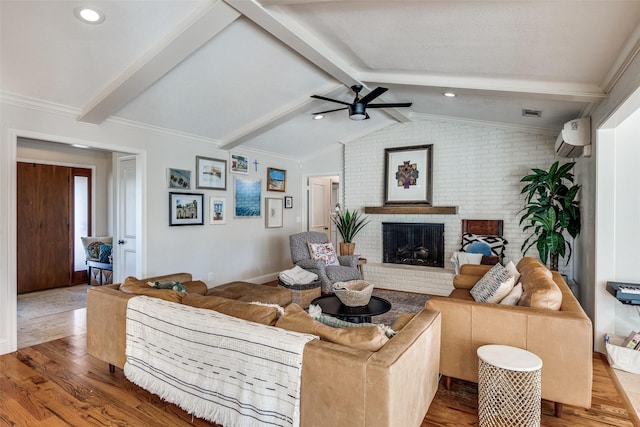 living room with ceiling fan, a wall mounted AC, a fireplace, vaulted ceiling with beams, and hardwood / wood-style flooring