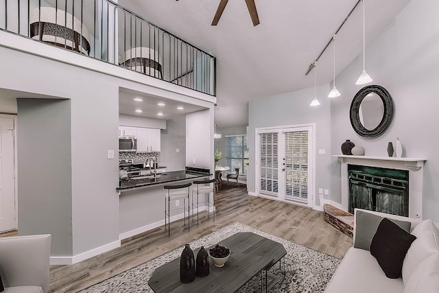 living room featuring light hardwood / wood-style flooring, ceiling fan, sink, a high ceiling, and rail lighting