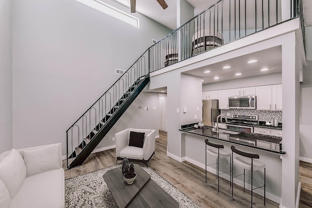 living area with stairs, a high ceiling, baseboards, and wood finished floors