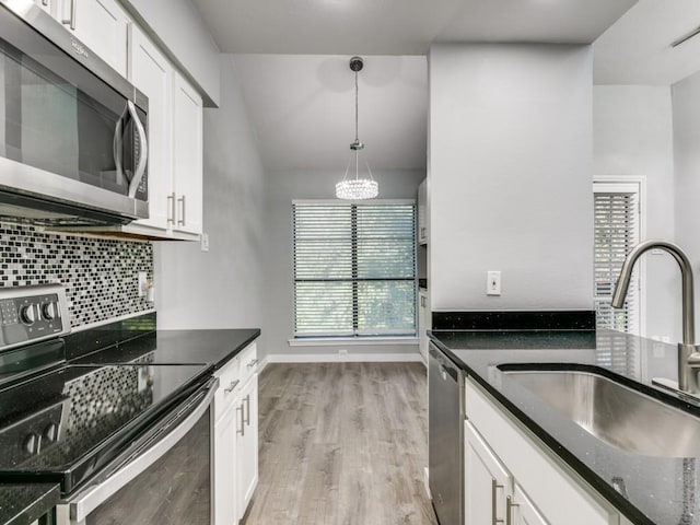 kitchen with white cabinets, decorative light fixtures, appliances with stainless steel finishes, and sink