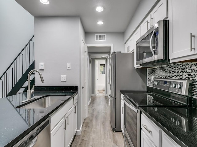 kitchen featuring sink, stainless steel appliances, white cabinetry, and dark stone counters